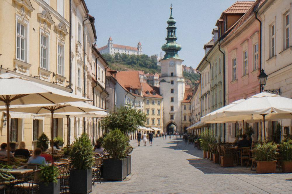 A pedestrian square with outdoor tables and coloured building facades in a European old town
