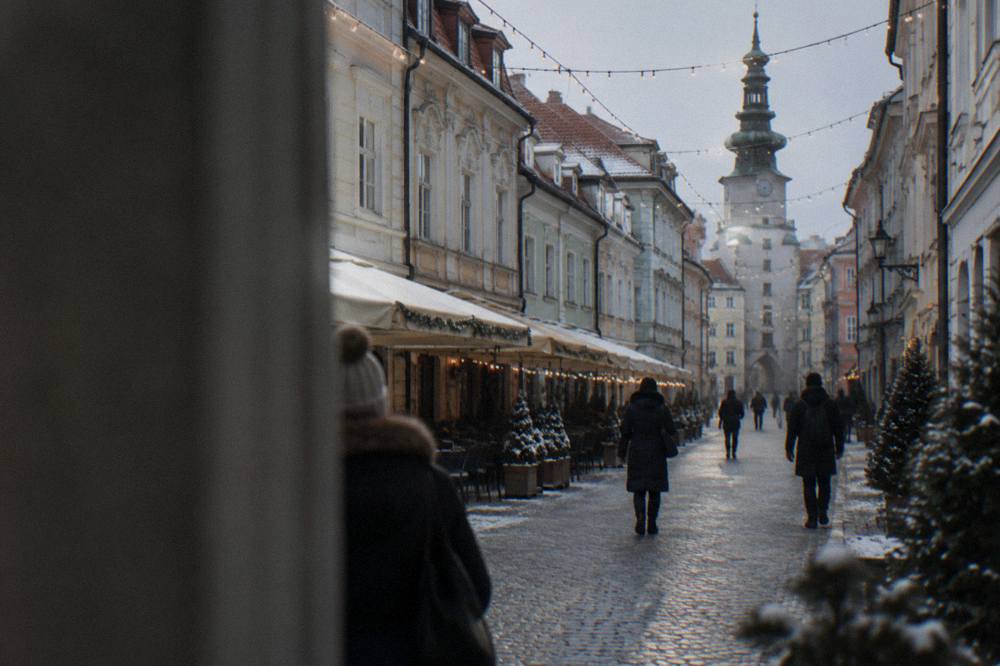 Festive lights over a narrow street in Bratislava's Old Town with people in winter coats