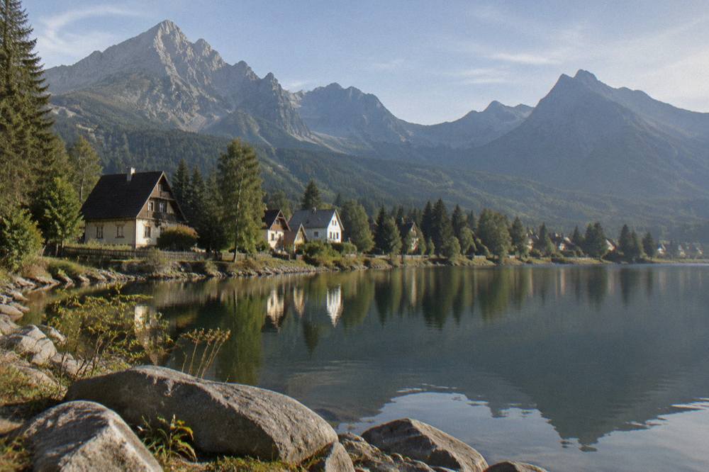 A wooden mountain village with traditional painted houses under forested slopes