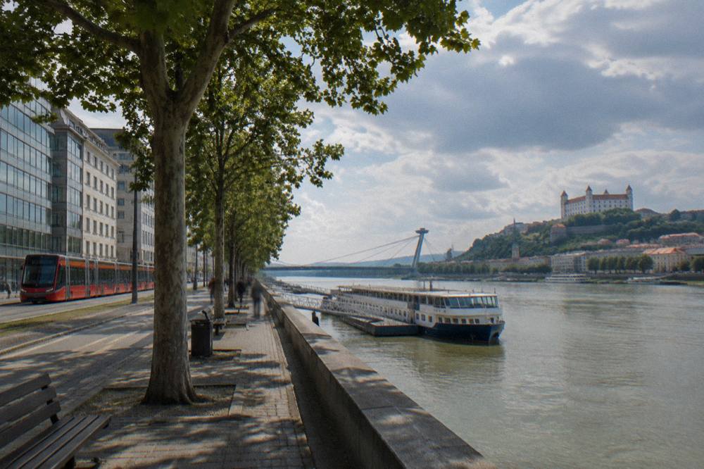 A tram passing modern buildings near the Danube riverfront in Bratislava
