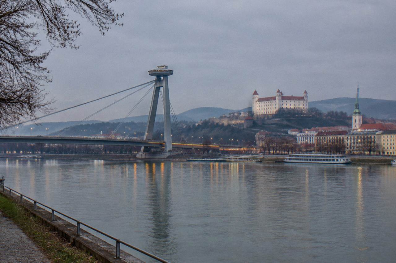 The UFO observation deck structure on the Most SNP bridge above the Danube in Bratislava, seen from the riverbank at dusk