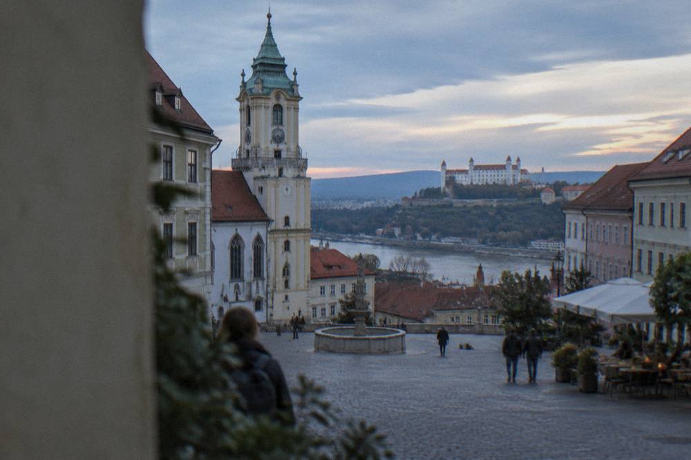 A view over Bratislava's red rooftops and the Danube river toward the castle hill in late afternoon light