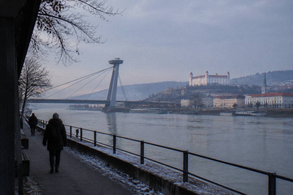 The Danube riverfront and SNP bridge in Bratislava under a pale winter sky