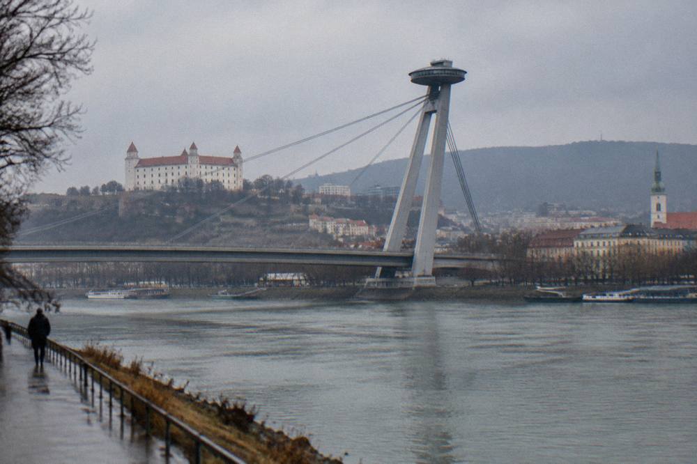 The Danube river in Bratislava with the UFO bridge tower and riverside buildings on both banks