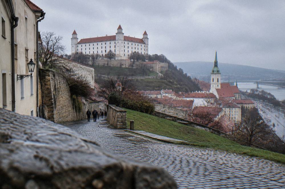 A cobbled street climbing the slopes of Podhradie toward the castle walls