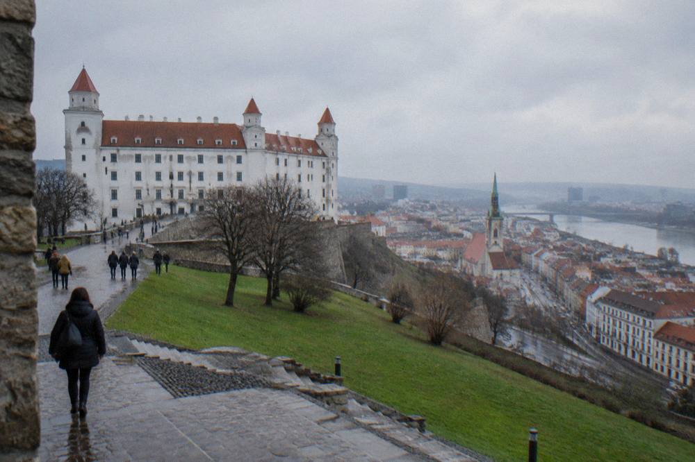 Visitors walking on the castle plateau with the city spread below