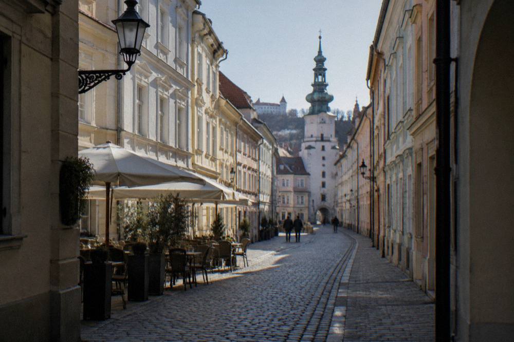 Narrow cobblestone street in Bratislava Old Town lined with pastel facades and lanterns