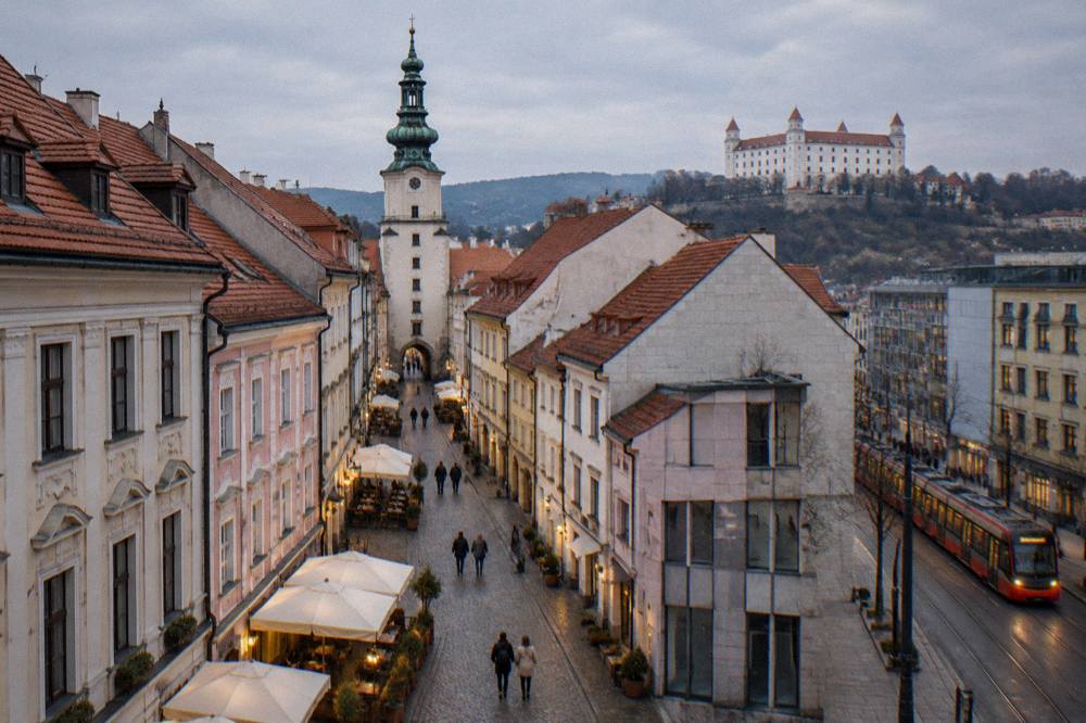 Tram passing modern buildings near the edge of Bratislava Old Town at dusk