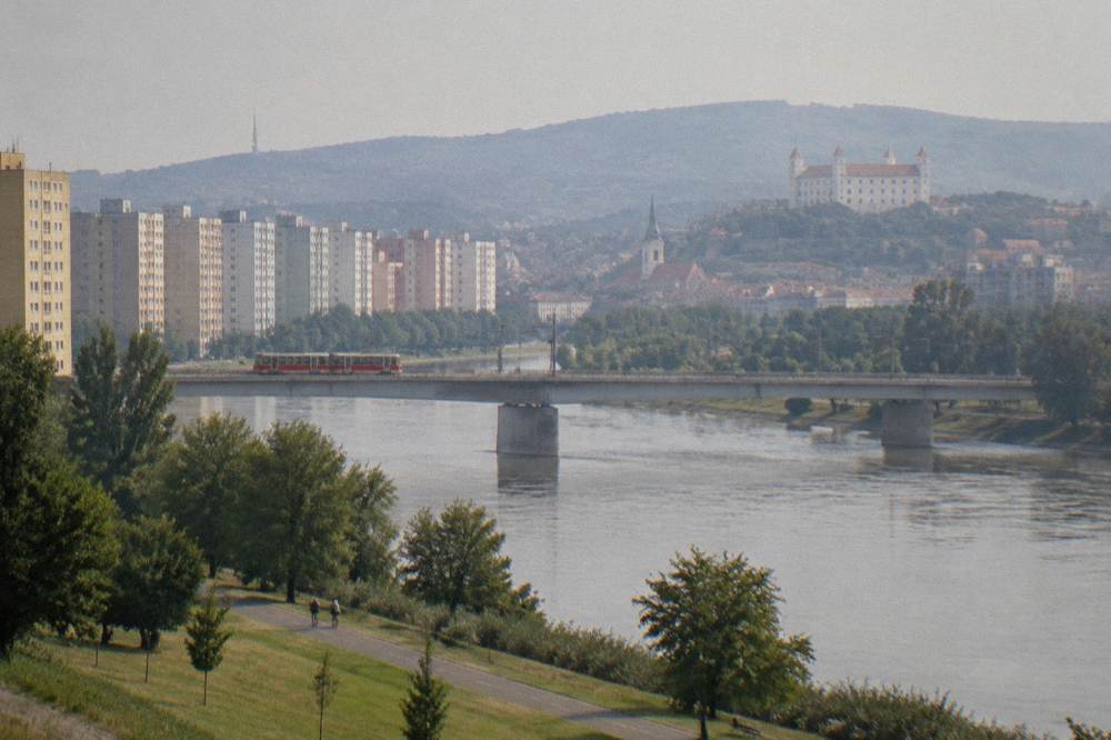 A tram crossing a bridge over the Danube toward rows of apartment blocks