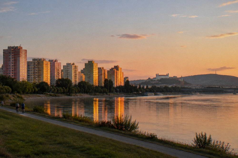 An evening view of lit apartment towers reflected in the Danube