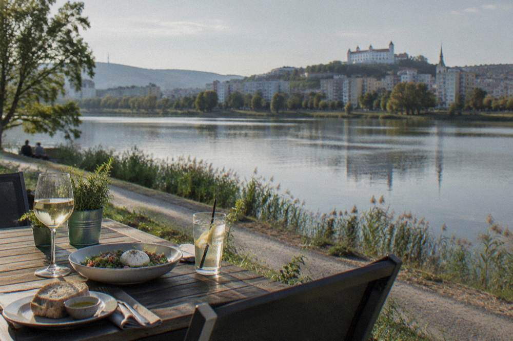 An outdoor restaurant table beside a lake at early evening
