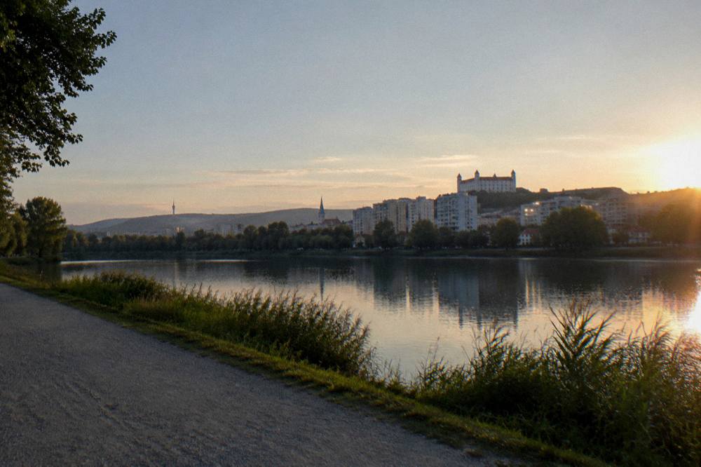 Evening light over a lake with the path empty and city lights beginning beyond