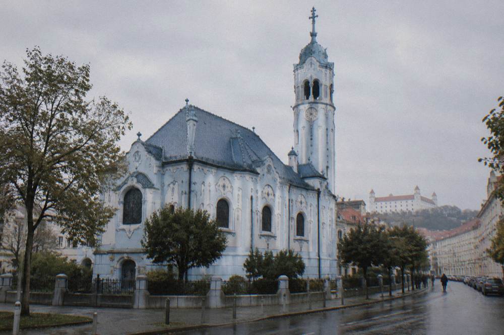 A side view of the Blue Church showing its blue roof and tower against the sky