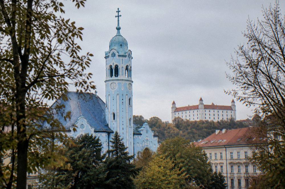 The tower of the Blue Church framed by trees in Bratislava