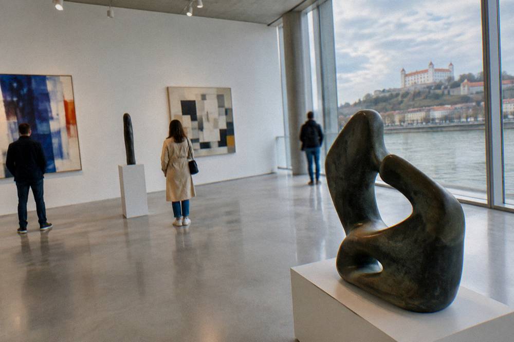 Visitors looking at abstract artwork inside a bright gallery hall