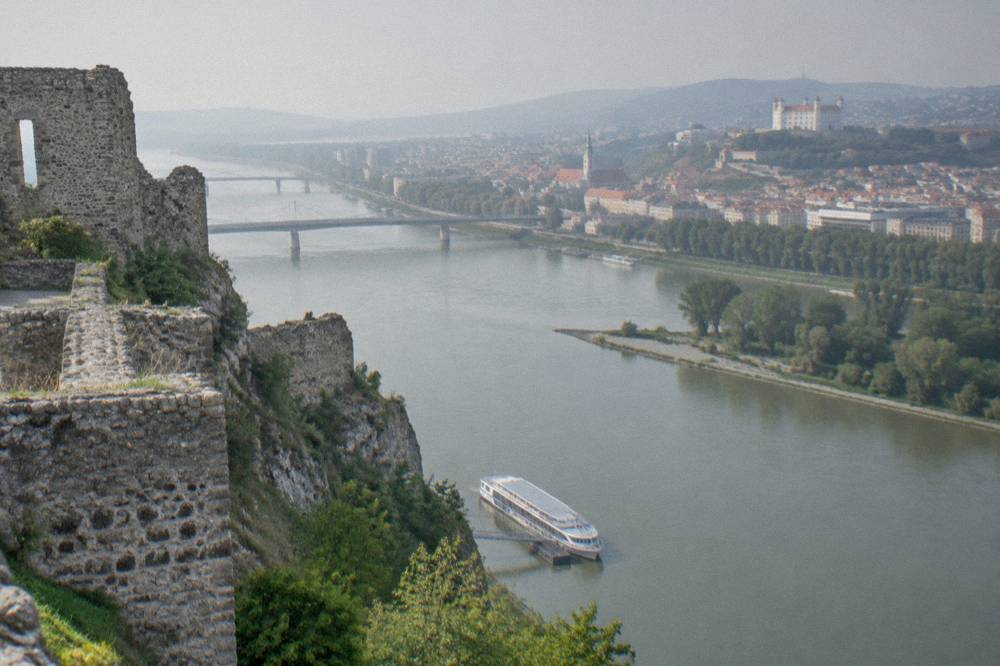 A riverboat moored at a small landing stage below a cliff with castle walls above