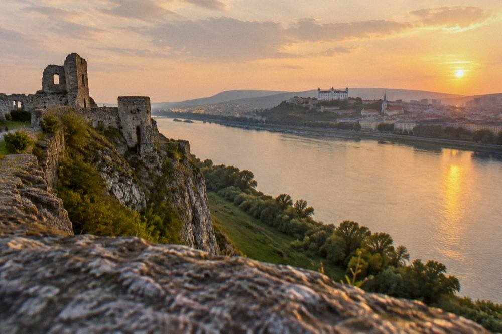 Evening light on a river with a castle cliff in the distance and a calm water surface