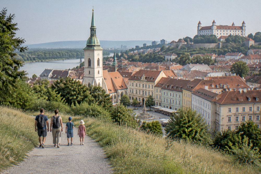 A family walking a wide gravel path through open hillside near Bratislava