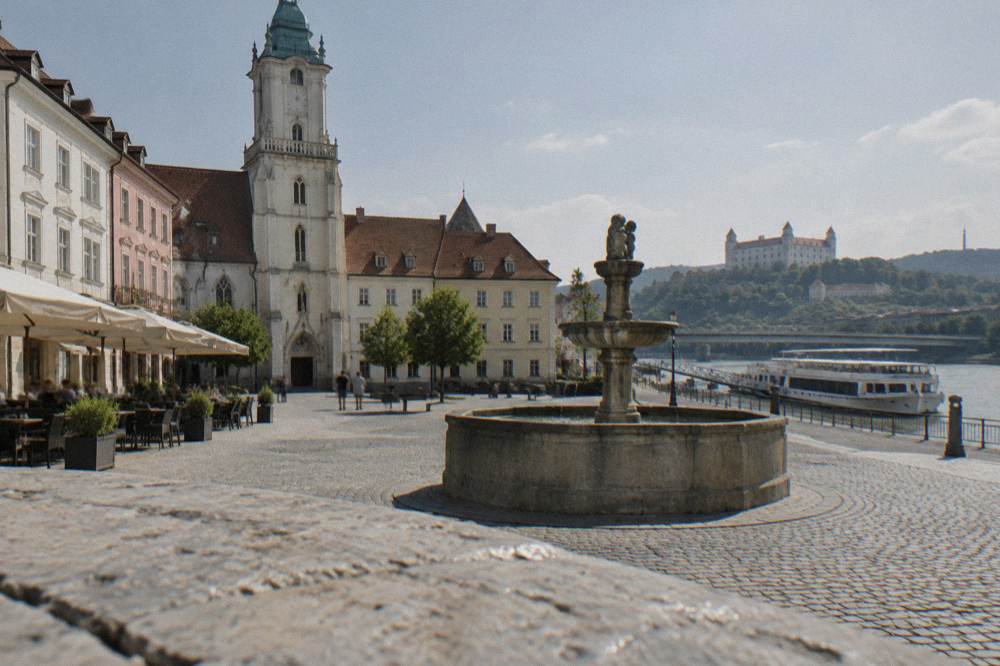 A Danube cruise boat moored at a riverside pier near a bridge in Bratislava