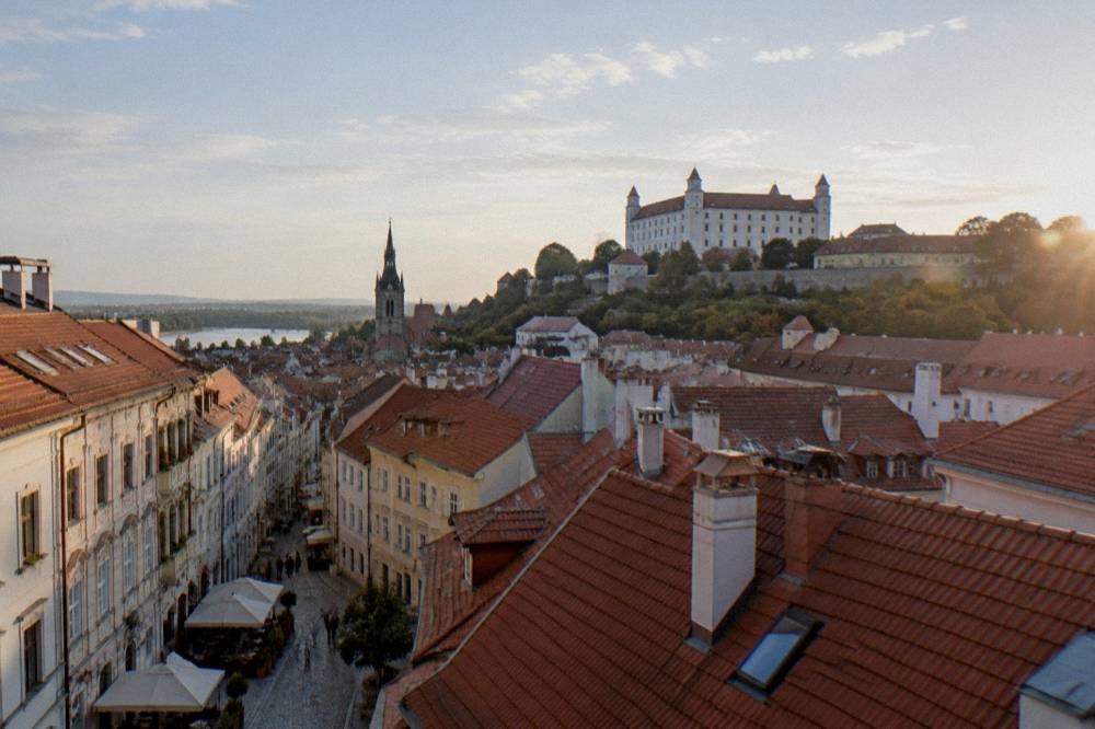 View from an Old Town tower over red rooftops toward Bratislava Castle