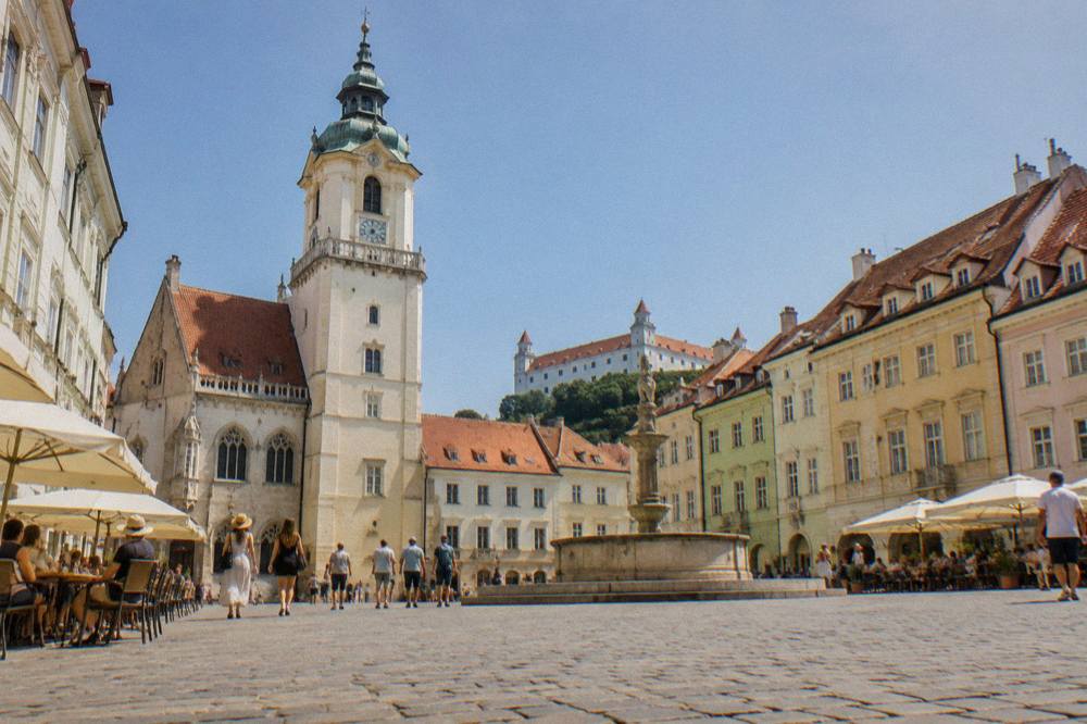 Café tables and pedestrians on Bratislava main square in summer