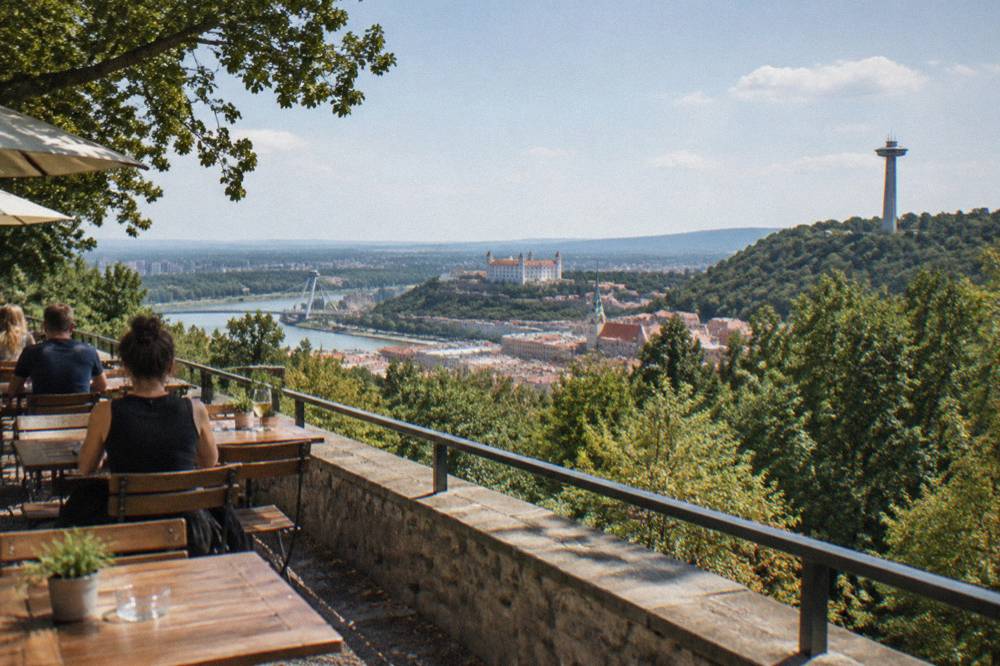 A hilltop restaurant terrace with tables looking out over treetops