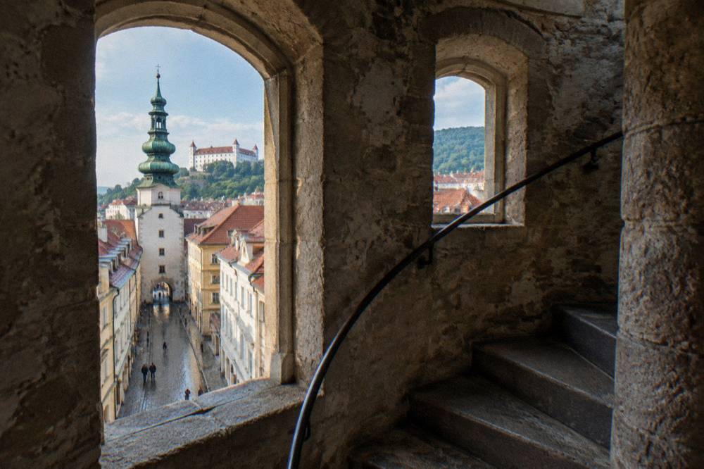A stone tower interior with a narrow spiral staircase and small arched windows