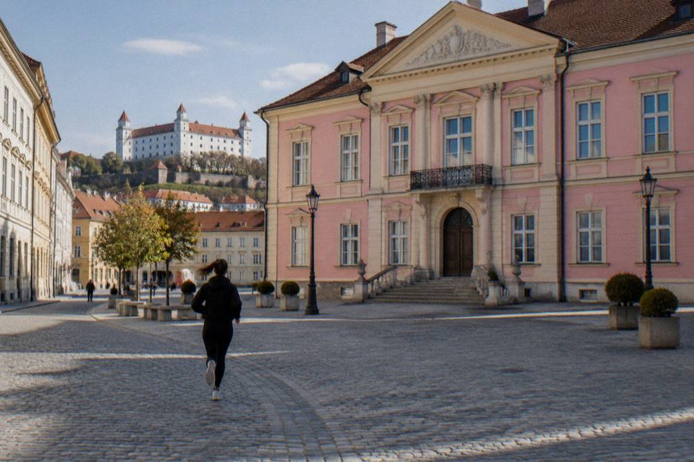 Pink and cream palace facade seen from a cobbled Bratislava square