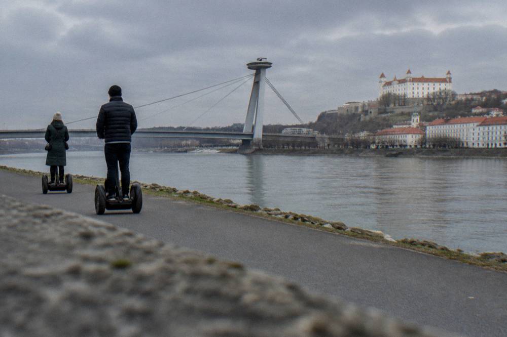 Segway riders on a riverside path with the UFO bridge in the background