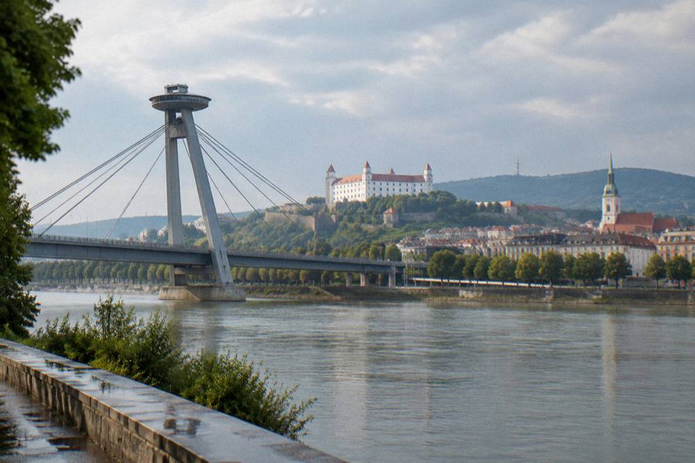 The UFO tower seen from the southern riverbank with the bridge road deck leading toward the Old Town