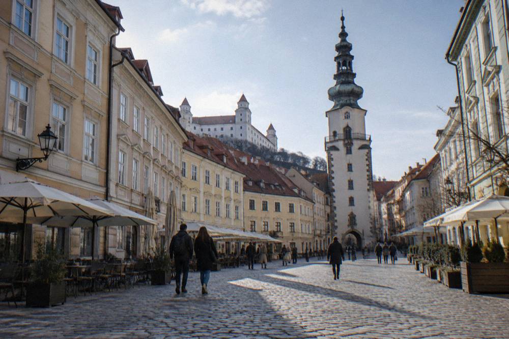 Visitors walking across a square in the Bratislava Old Town on a bright day