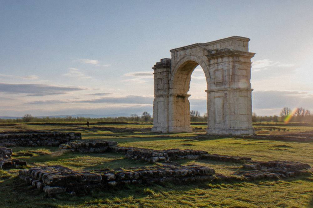 Low stone foundations of ancient buildings laid out across a grassy field