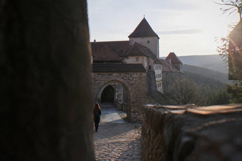 A stone gate and walls of a Small Carpathian castle seen from the approach path