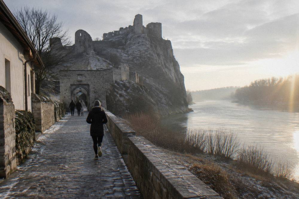 A castle gate and stone walls in low winter light above a wide river