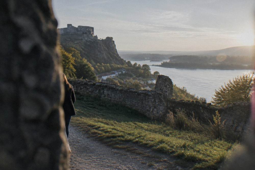 Walking path along grassy ruins with the river visible beyond the walls