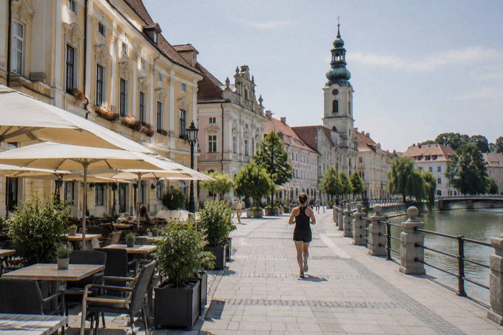 Café tables on a sunny square with ornate building facades behind