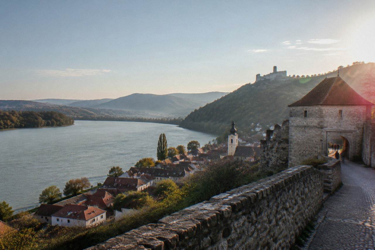 A small Austrian town on the Danube river with a hilltop castle ruin above the rooftops