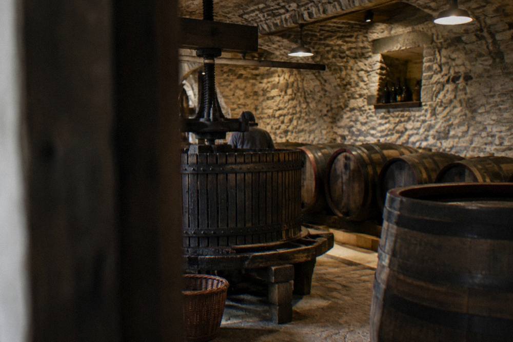 An old wine press and barrels inside a stone cellar