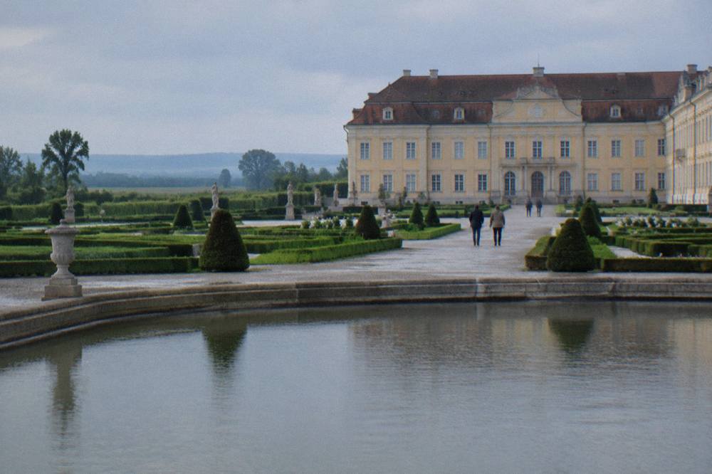 Formal garden parterres with clipped hedges and gravel paths leading to a palace
