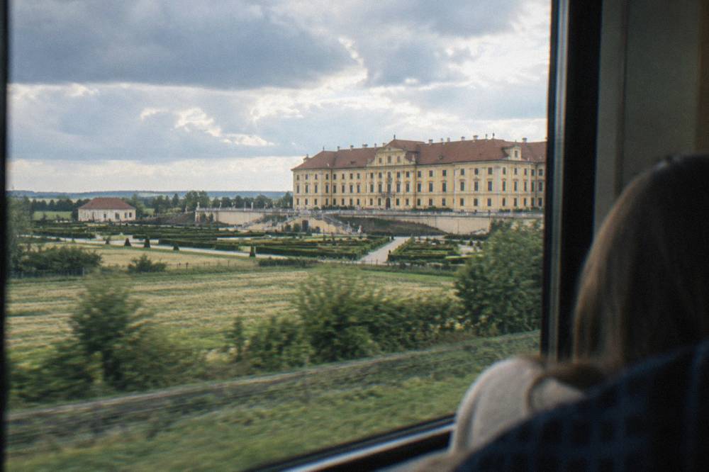 A regional train travelling through open countryside toward a river town