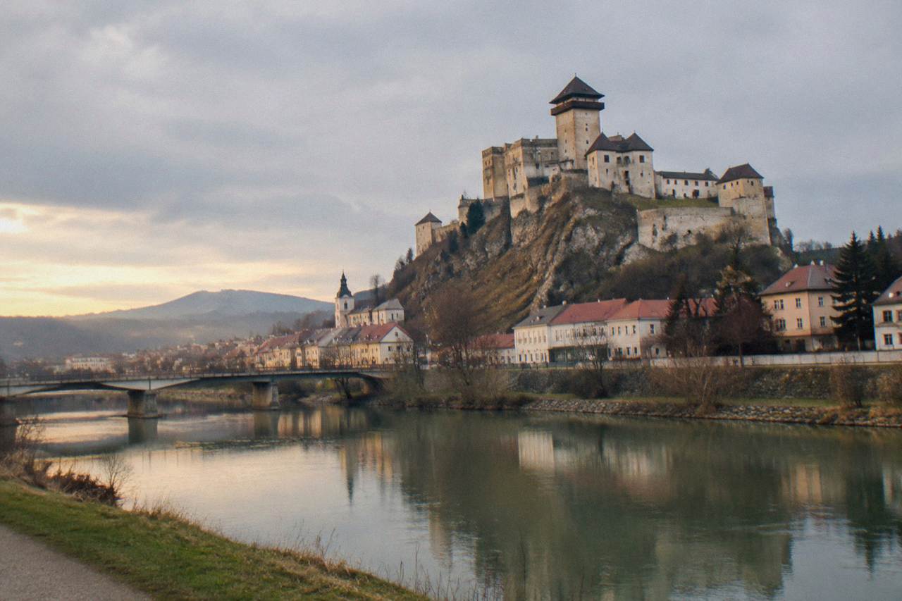 A medieval castle on a rocky hill above a small European town at golden hour
