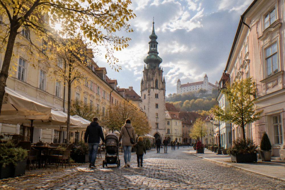 Family walking through an old town square with a pushchair in autumn