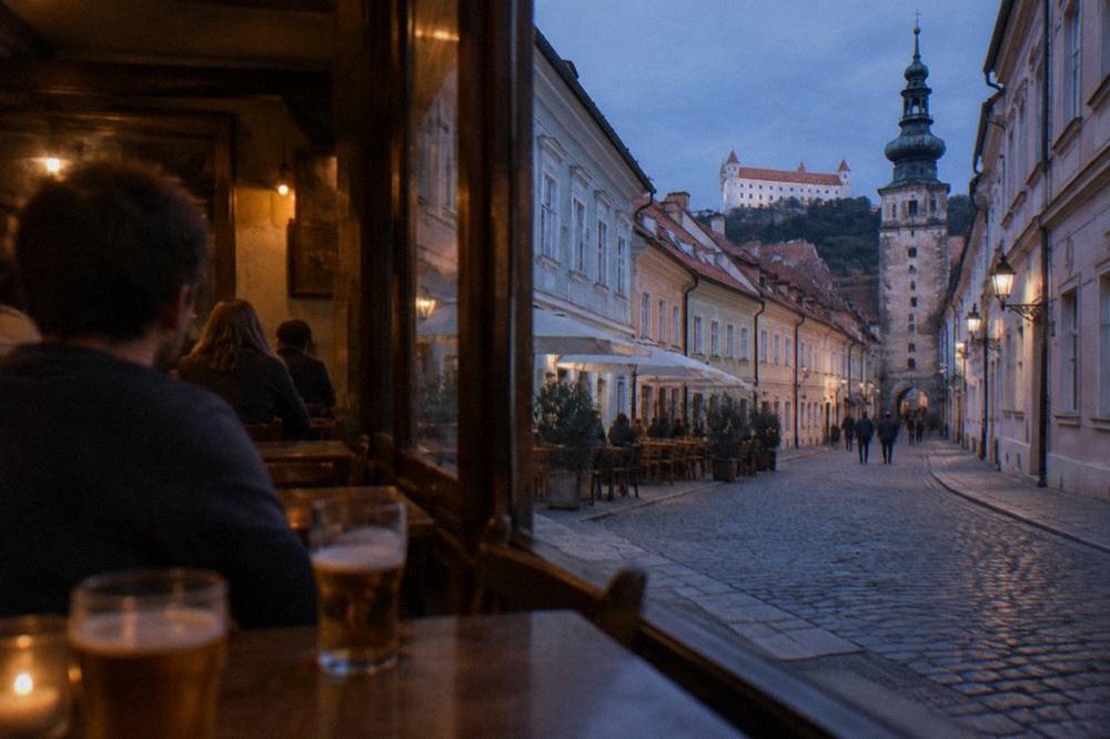 People sitting at wooden tables in a dim pub interior with glasses of beer