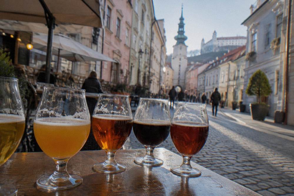 Row of stemmed tasting glasses with different coloured beers on a bar top