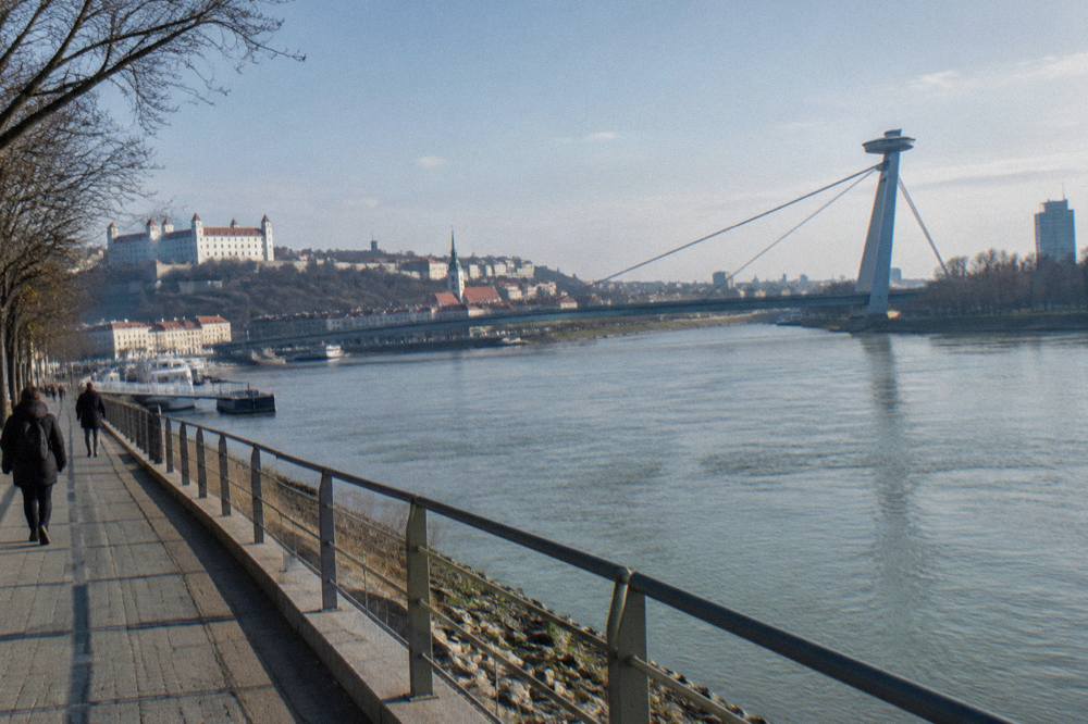 The Danube riverfront in Bratislava with the UFO bridge in the background on a clear day