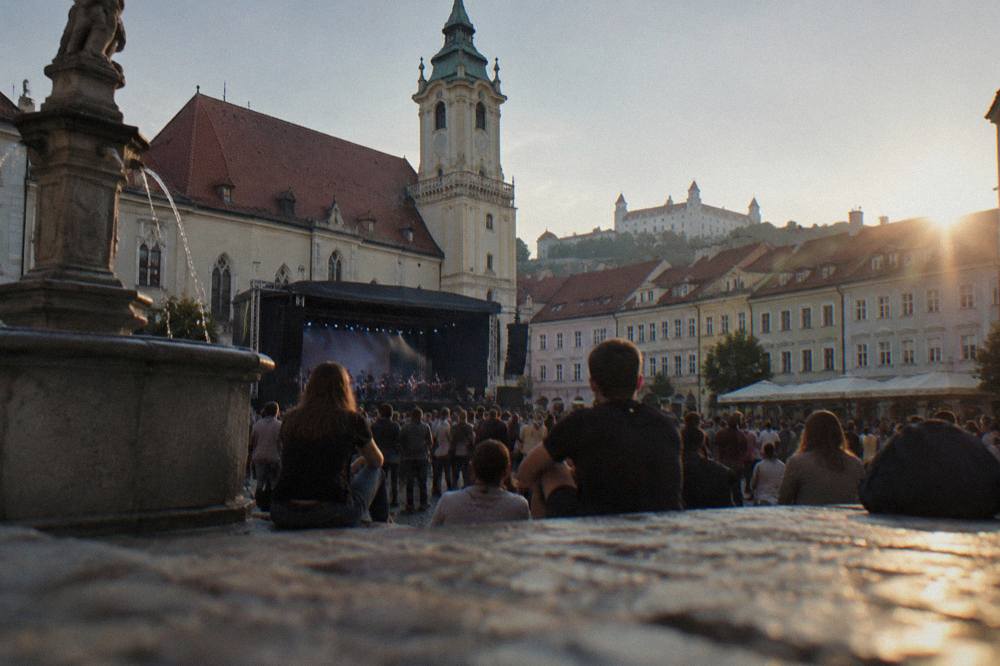 A concert crowd outside a historic hall in central Bratislava during an evening event