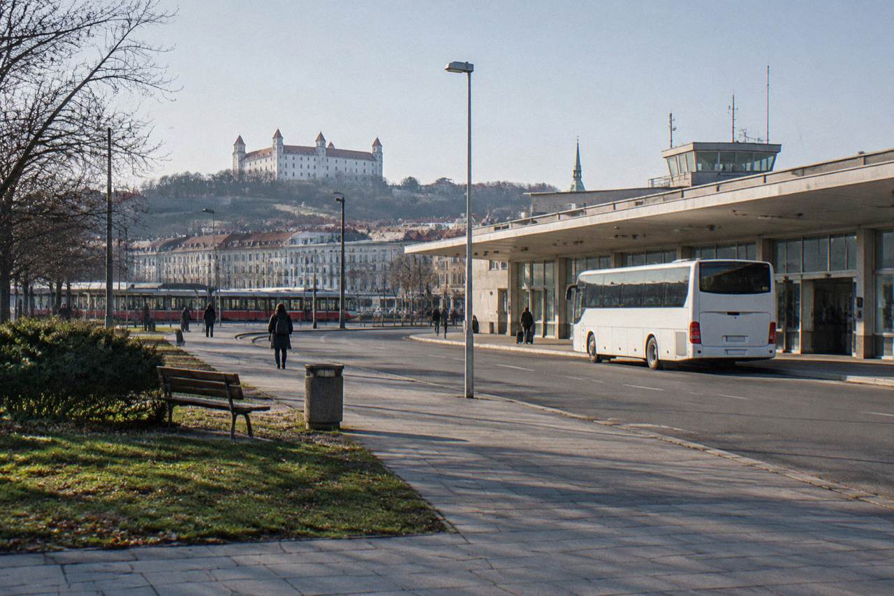 A bus parked outside a small airport terminal building on a clear day