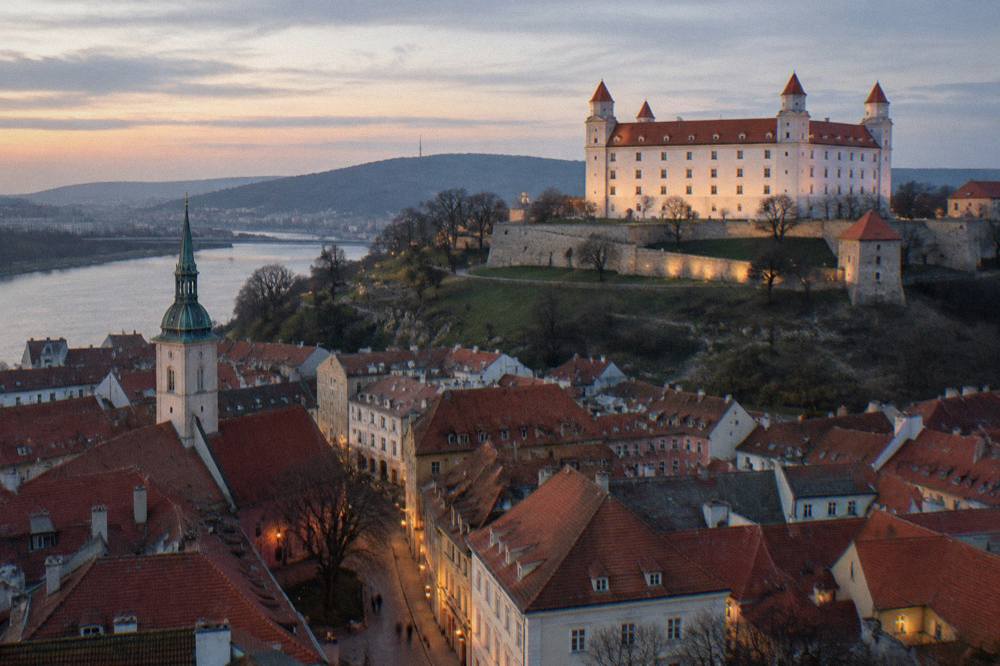 Evening view of Bratislava castle and old town rooftops lit after sunset