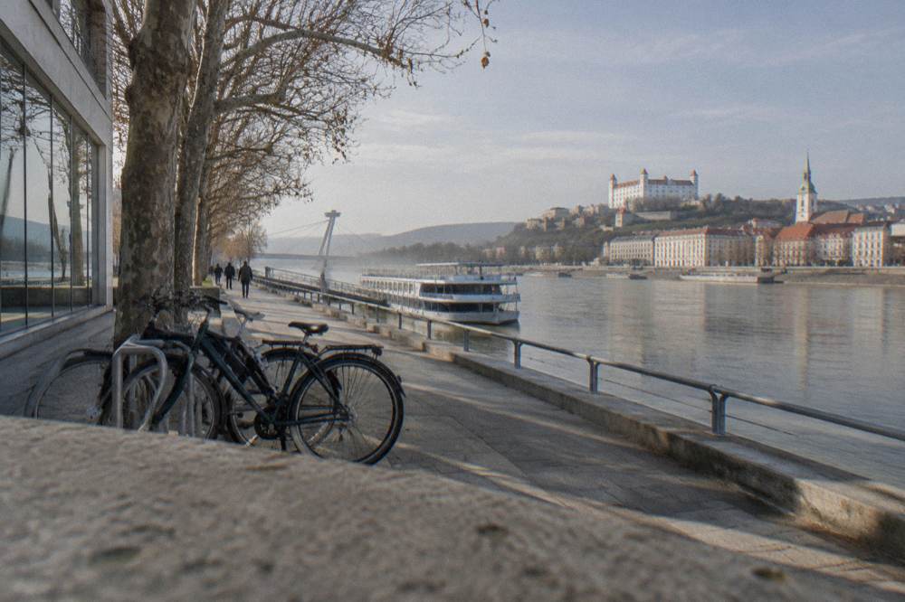 Bicycles parked outside a modern gallery building beside a wide river