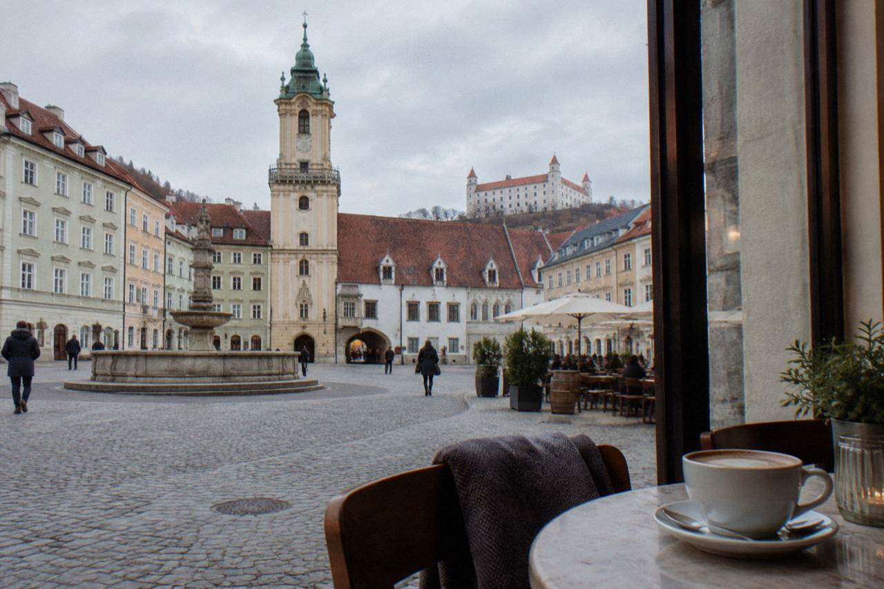 A coffee cup on a small table beside a window in a Bratislava café